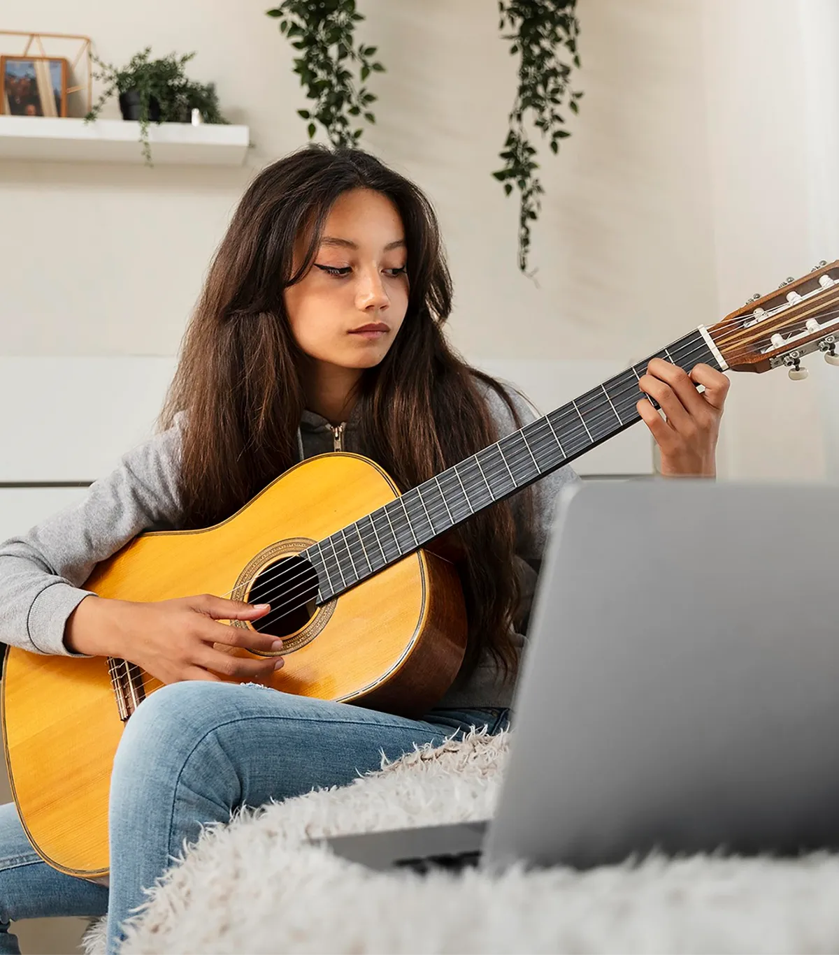 Student playing guitar during online lesson